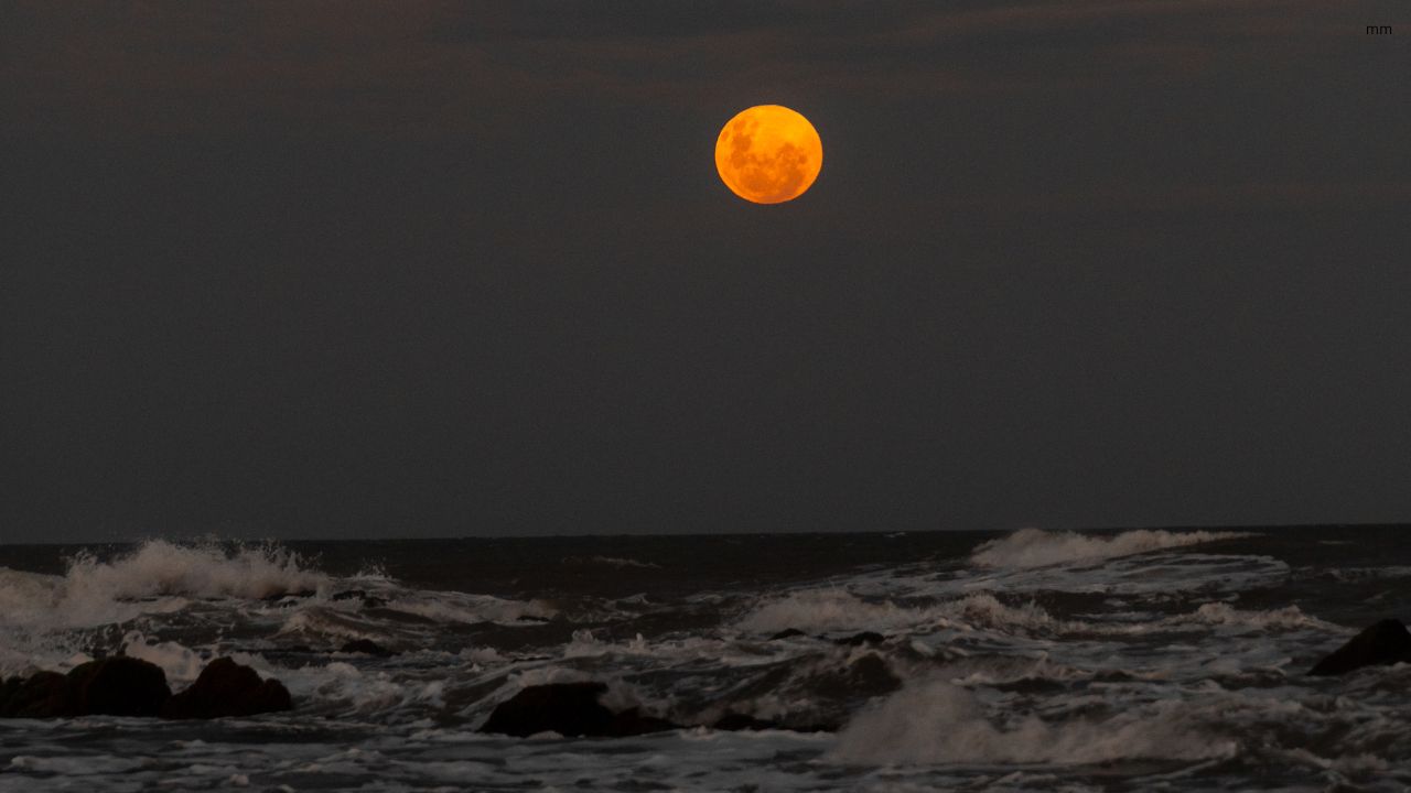 Moon reflecting over ocean waves during high tide
